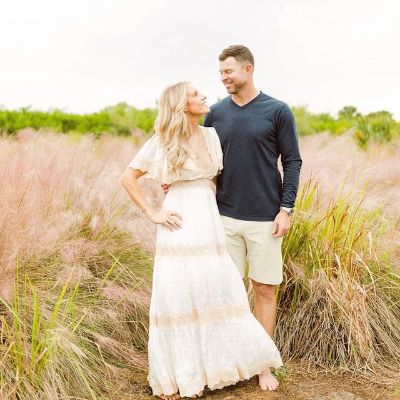 Corey Kluber is wearing a black tee with white shorts and Amanda Kluber is wearing a white dress in the picture.